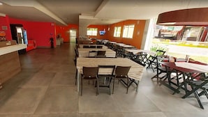 A spacious restaurant with high tables and chairs, a counter, and red walls.