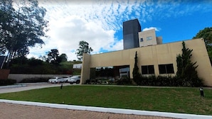 A modern building with a flat roof, large windows, and a parking lot with several cars.