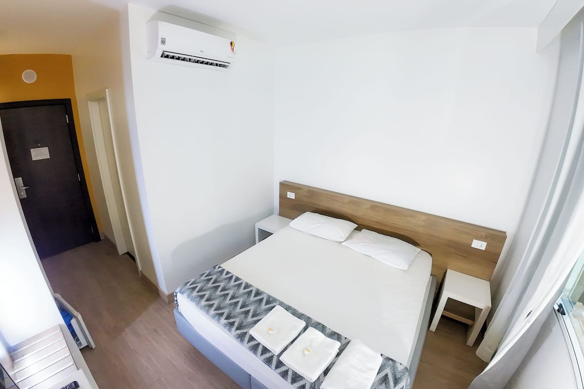Ein Schlafzimmer mit einem Bett, Nachttischen, einem Holzkopfteil und einer Klimaanlage.
