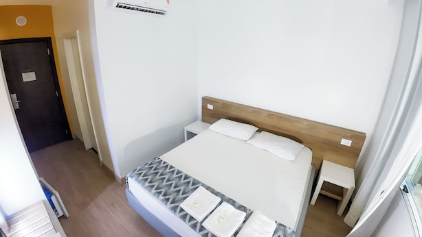 A bedroom with a bed, bedside tables, a wooden headboard, and an air conditioning unit.