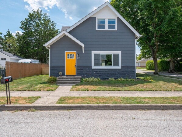 A two-story house with a yellow front door, a small front porch, and a mailbox. - Your Greenfield Getaway (Greenfield)
