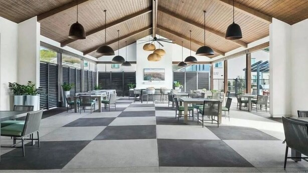 A spacious indoor area with high ceilings and wooden beams, featuring multiple tables and chairs arranged for dining or socializing. - Charming townhome with WiFi, AC, Pool and Community Center in Peaceful Fallbrook (Fallbrook)