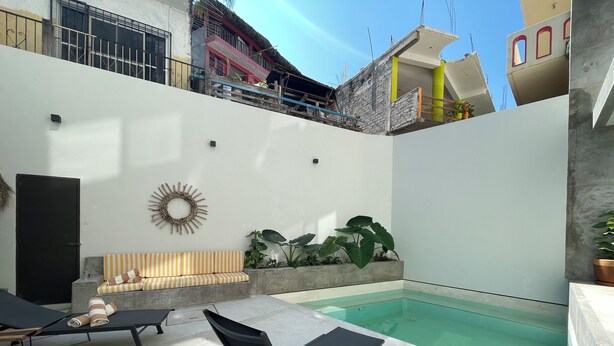 A rooftop pool area with lounge chairs, a sun lounger, and a small seating area with cushions. - Rooms Zicatela (Puerto Escondido)
