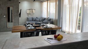 A modern dining area with a wooden table, chairs, and a cutting board with apples and a knife. - Rooms Zicatela (Puerto Escondido)