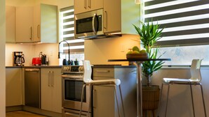 Une cuisine moderne équipée d’appareils électroménagers en acier inoxydable, d’une machine à café et agr émentée d’une plante en pot.