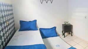 A room with two beds, a small bedside table with a plant, and a decorative wall piece. - Charming 3 bedroom house COP (Umarizal Belém)