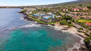 A coastal hotel with multiple buildings, a beach, and clear turquoise waters.