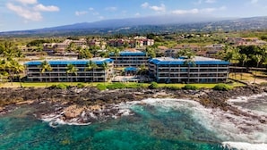 A resort with multiple buildings, a rocky shoreline, and clear turquoise waters.