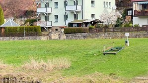 Un bâtiment à deux étages, doté d’un toit rouge et de nombreux balcons, situé au bord d’un plan d’eau.
