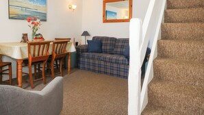 Ein Wohnzimmer mit Esstisch, Stühlen, einer Couch und einer Treppe.