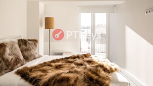 Ein Schlafzimmer mit einem großen Bett, einem Fellüberwurf, einer Lampe und Blick ins Freie.