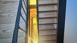 Eine Holztreppe mit Metallgeländer und einer Leuchte in der Mitte.