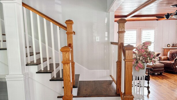 Eine Holztreppe mit weißen Wänden und Holzboden, die zu einer zweiten Etage führt.