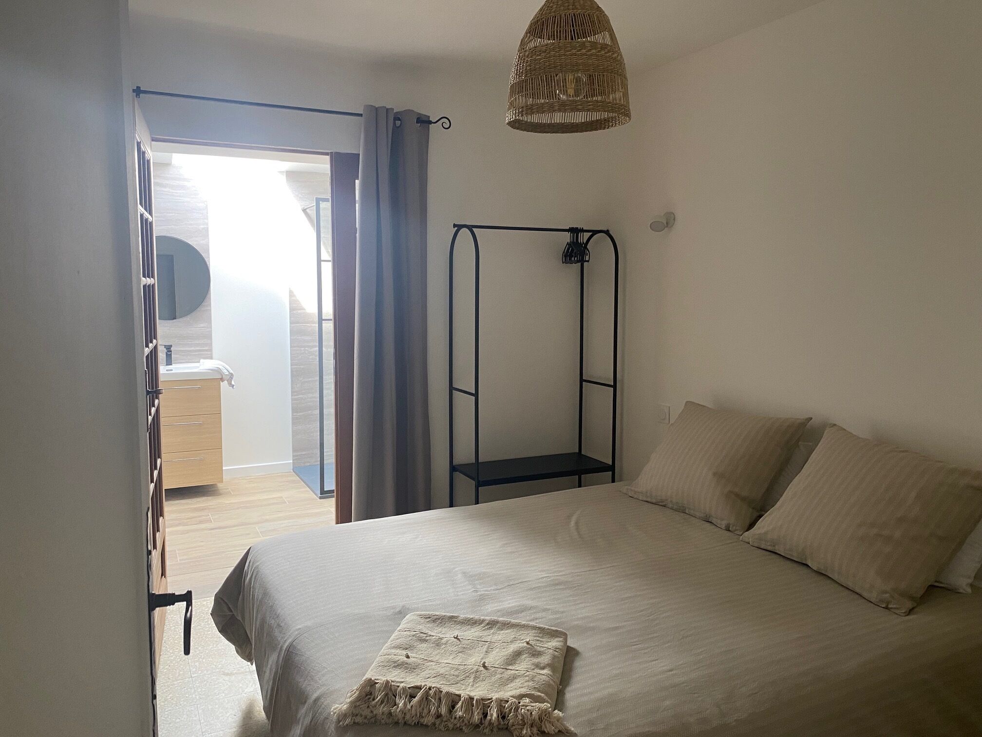 Ett sovrum med en säng, en hängande lampa, en garderob och utsikt över ett utomhusområde.