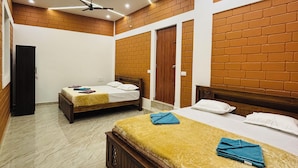 A hotel room with two beds, a ceiling fan, and a brick wall design.