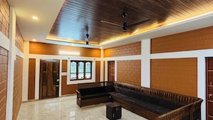 A spacious room with a large wooden bench, a ceiling fan, and a brick wall.