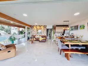 A spacious living area with a large sofa, dining table, and a kitchen in the background. - Cabaña Jacuzzi Paisaje Vista Increible Altos Maria (Sorá)
