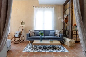 A living room with a sofa, a rocking chair, a coffee table, and a patterned rug.
