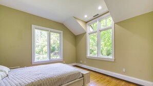 A bedroom with a bed, two windows, and a sloped ceiling. - 18 Mi to Boston - Stylish Unit in Upscale Enclave! (Weston)