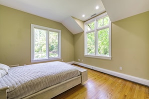 Una camera da letto con un letto, due finestre e un soffitto spiovente.