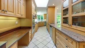 A kitchen with wooden cabinets, a granite countertop, and a skylight. - 18 Mi to Boston - Stylish Unit in Upscale Enclave! (Weston)