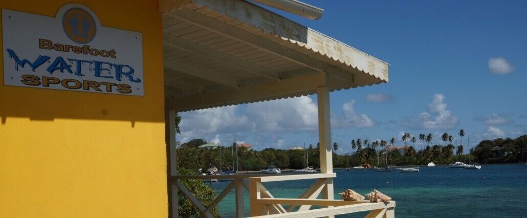 A beachside bar with a sign for 'Barefoot Water Sports'.
