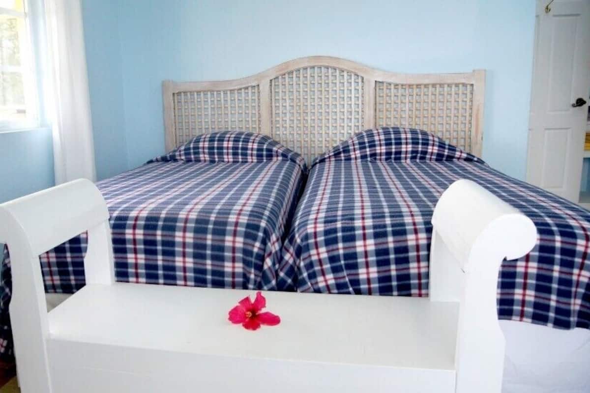Un lit avec une couvre-lit à carreaux et une tête de lit blanche, dans une pièce aux murs bleu clair.