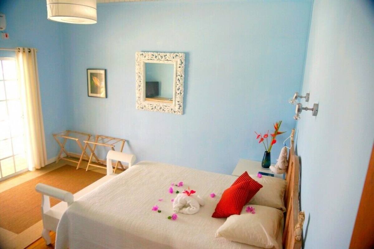 Une chambre à coucher avec un lit, une table de chevet, un miroir et une fenêtre avec des rideaux.