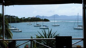 A view of the sea with several boats anchored, a beach, and mountains in the background. - Barefoot Suites (Ratho Mill)
