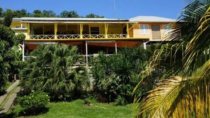 A two-story building with a balcony and a garden with palm trees. - Barefoot Suites (Ratho Mill)