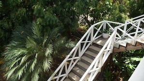 A white staircase with a geometric railing design, surrounded by lush greenery and trees. - Barefoot Suites (Ratho Mill)