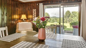 A wooden-paneled room with a table, a vase of flowers, and a view of the outdoors. - Tee Off in the Mtns: Sky Valley Condo w/ View! (Dillard)
