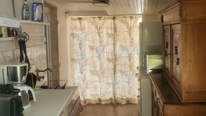 A kitchen with wooden cabinets, a microwave, and a refrigerator. - Charming Provencal country house in the heart of the Alps de Haute Provence 3*. (Mézel)
