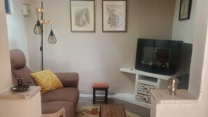 A living room with a sofa, a small table, a TV, and framed artwork on the wall. - Charming Provencal country house in the heart of the Alps de Haute Provence 3*. (Mézel)