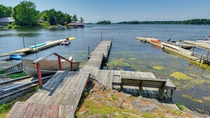A wooden dock extending into a calm lake with boats moored at the end. - Fishing & Boating Paradise: St Lawrence River Home (Hammond)