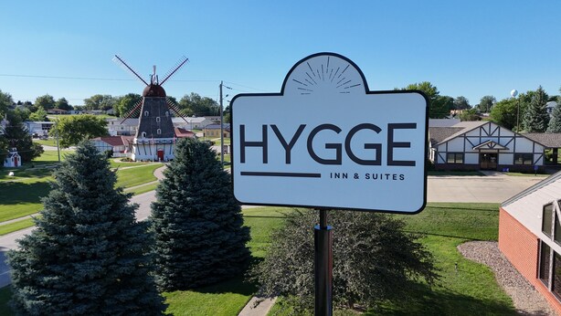 Un letrero para Hygge Inn & Suites con un molino de viento al fondo.