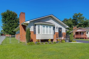 A single-story house with a brick chimney, white siding, and a front porch with a railing. - Charming Kingsport Home w/ Spacious Fenced Yard! (Kingsport)
