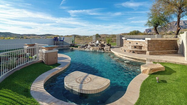 Piscina com deck de pedra, área cercada com assentos e vista da paisagem ao redor.