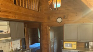 A cozy cabin with a kitchen, a dining area, and a loft bedroom. - Lomahyppäys (Naantali)
