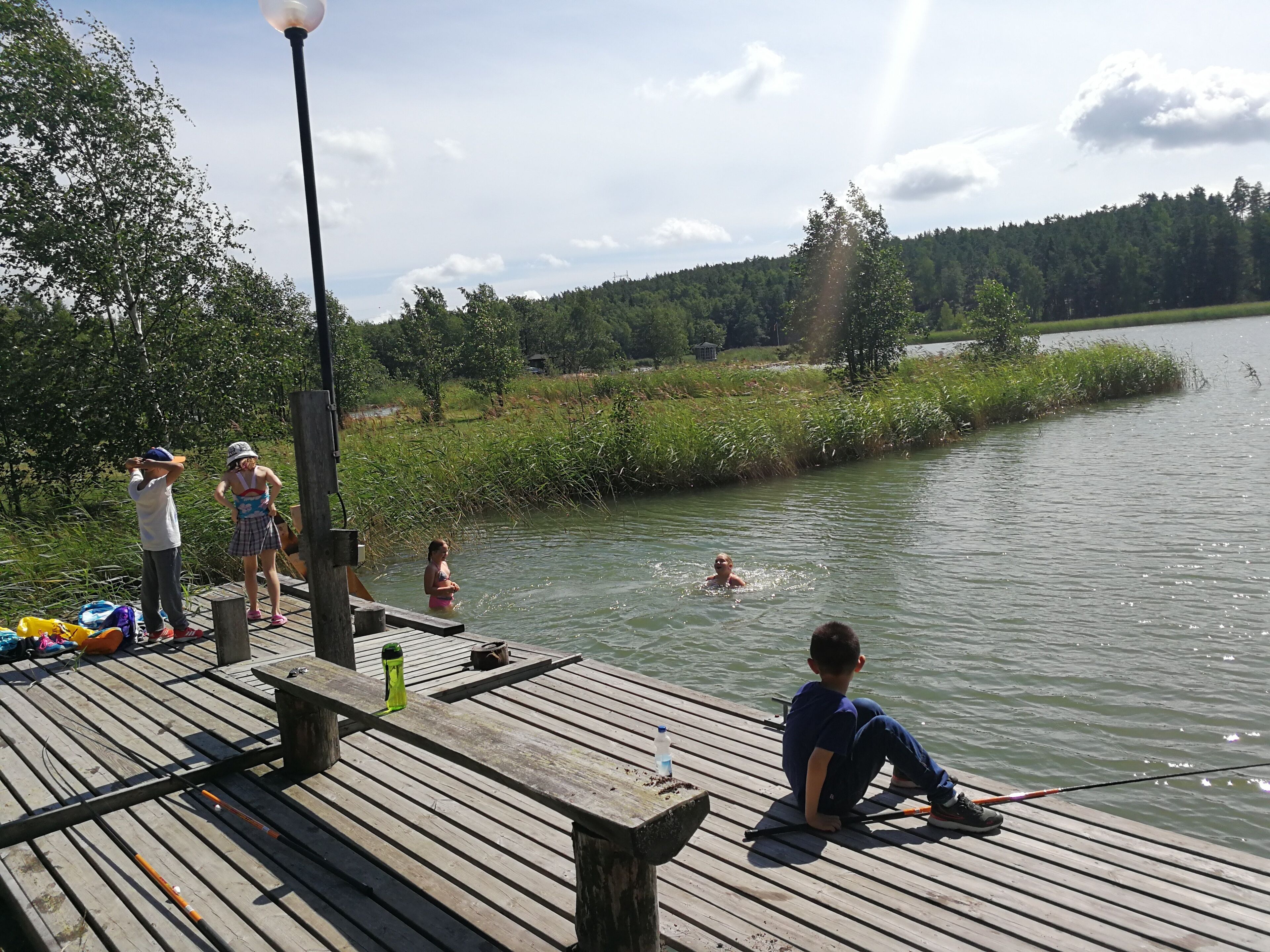 A wooden dock extending into a body of water with people engaging in water activities.