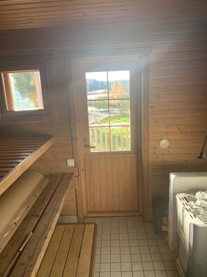 A wooden cabin with a view of a lake and trees through a door.