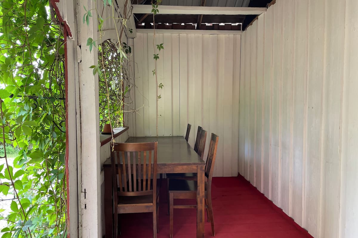 A dining area with a wooden table and chairs, surrounded by white walls and a red carpet.