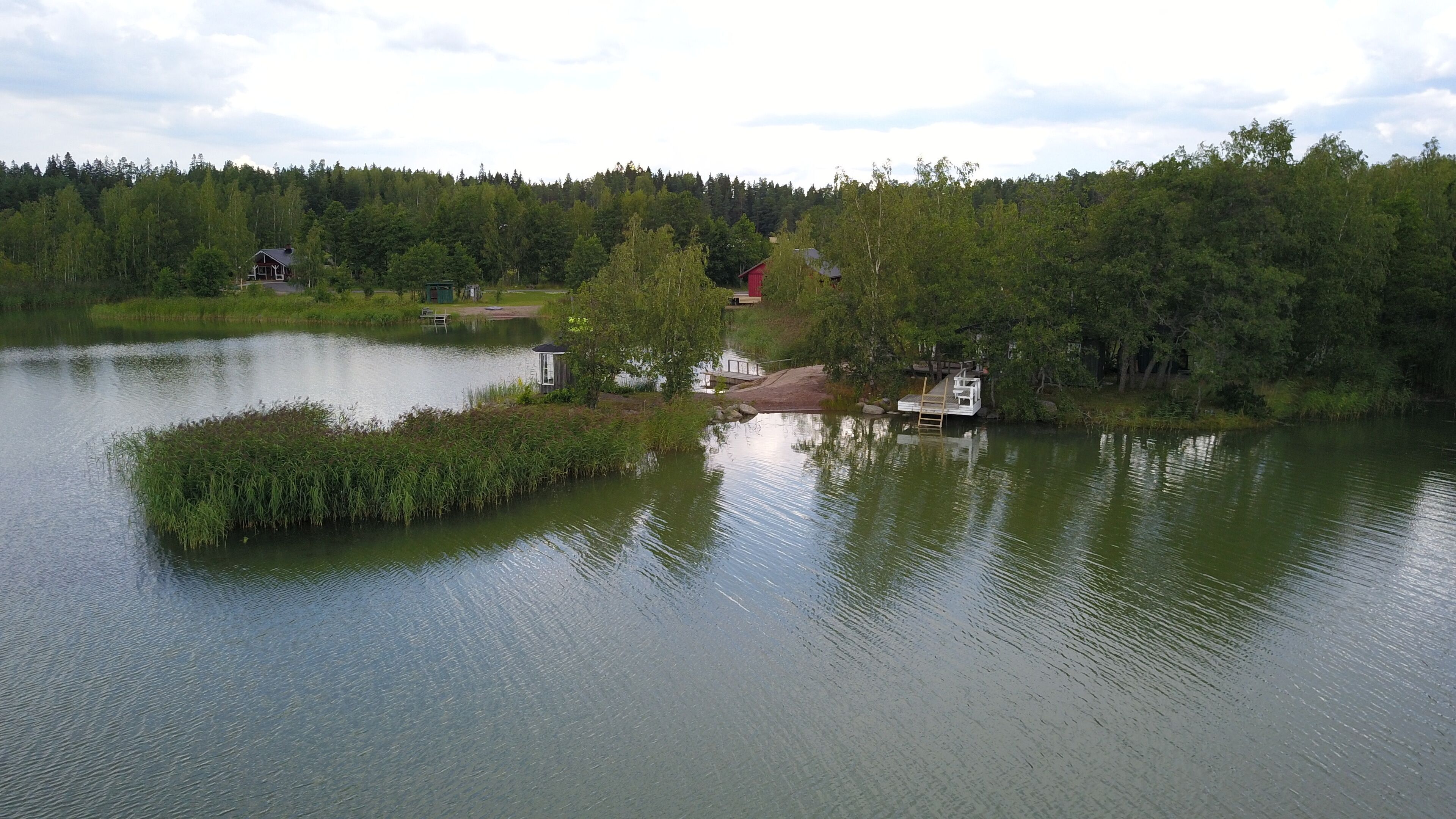 A lakeside cabin with a dock, surrounded by dense forest and a calm lake.