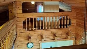 A wooden interior with a balcony, a clock, and a window with curtains. - Lomahyppäys (Naantali)