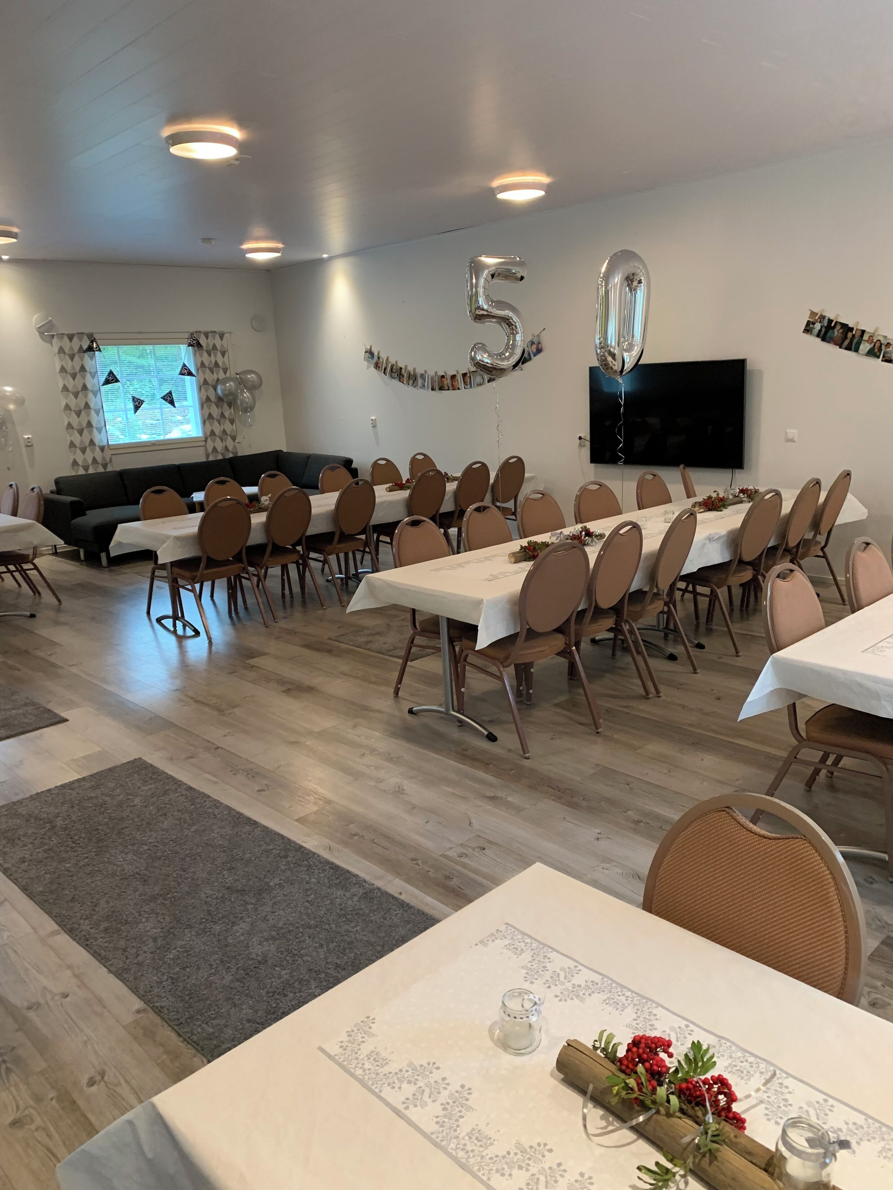 A conference room with a long table, multiple chairs, a sofa, and a TV screen.