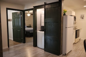 Una habitación con cama, lavadora, refrigerador y espacio para cocinar.