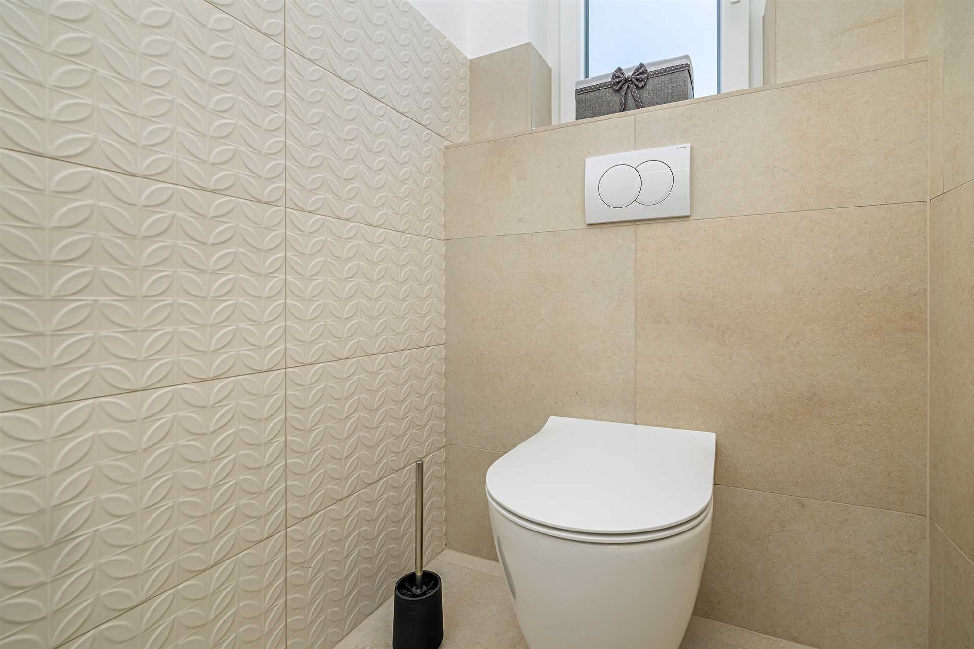 Ein Badezimmer mit Toilette, einem Handtrockner und gemusterten Fliesen.