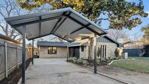 Un espacio de patio cubierto con fachada de piedra y estructura de techo metálico.