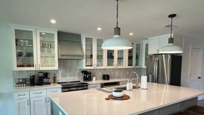 Una cocina moderna con una isla grande, muebles blancos y electrodomésticos de acero inoxidable.