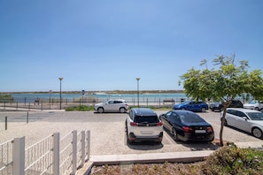Un estacionamiento con coches, cielo despejado y vista al mar.